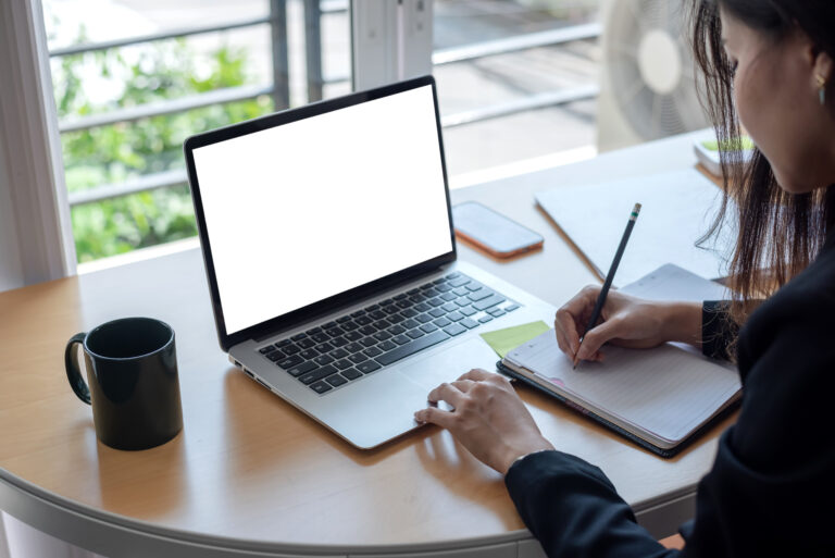 Image of young businesswoman taking notes using a laptop blank w